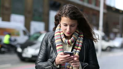 File:Stock-footage-attractive-young-woman-using-a-smart-phone-and-looking-around-whilst-out-on-a-public-street.jpeg