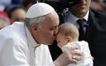 The Pope kisses a baby.