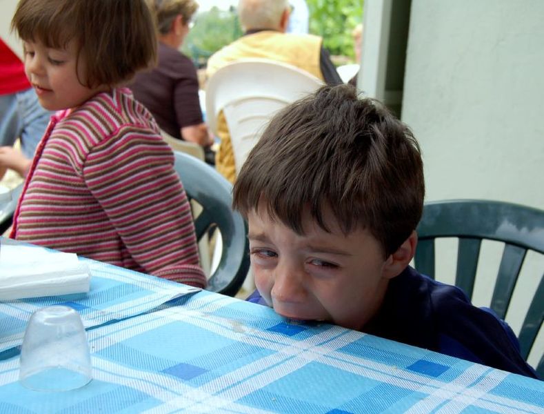 Datei:Kind beißt in tisch.jpg