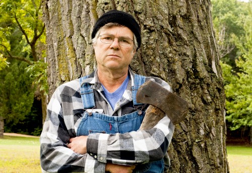 File:Man-holding-an-axe-leaning-against-a-tree.jpg