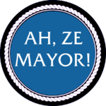 A circular blue badge with white text reading "Ah, Ze Mayor!"