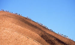 Space tourist climbing into space on Uluru in the Australian Outback.